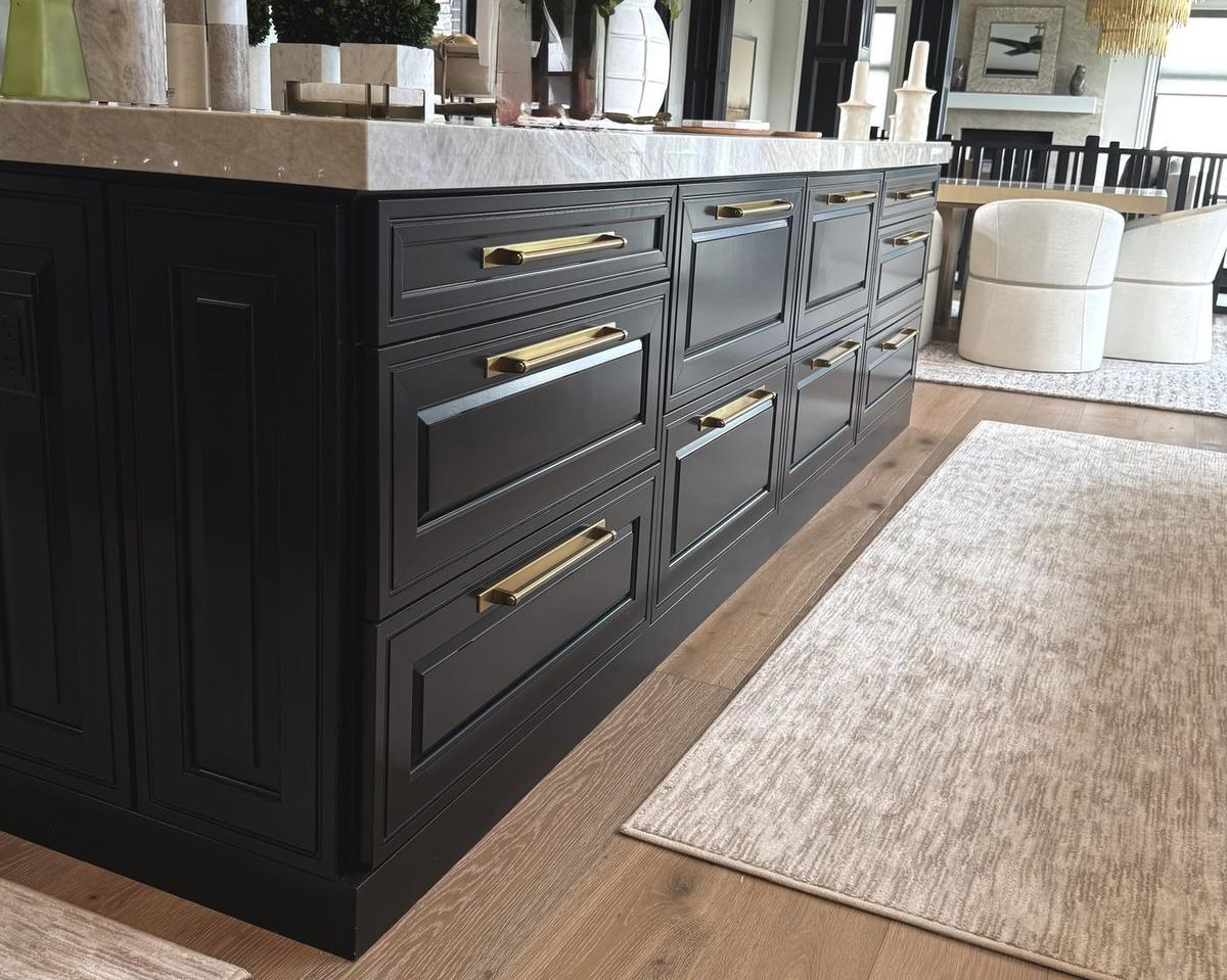 Black painted island cabinetry with brass pulls