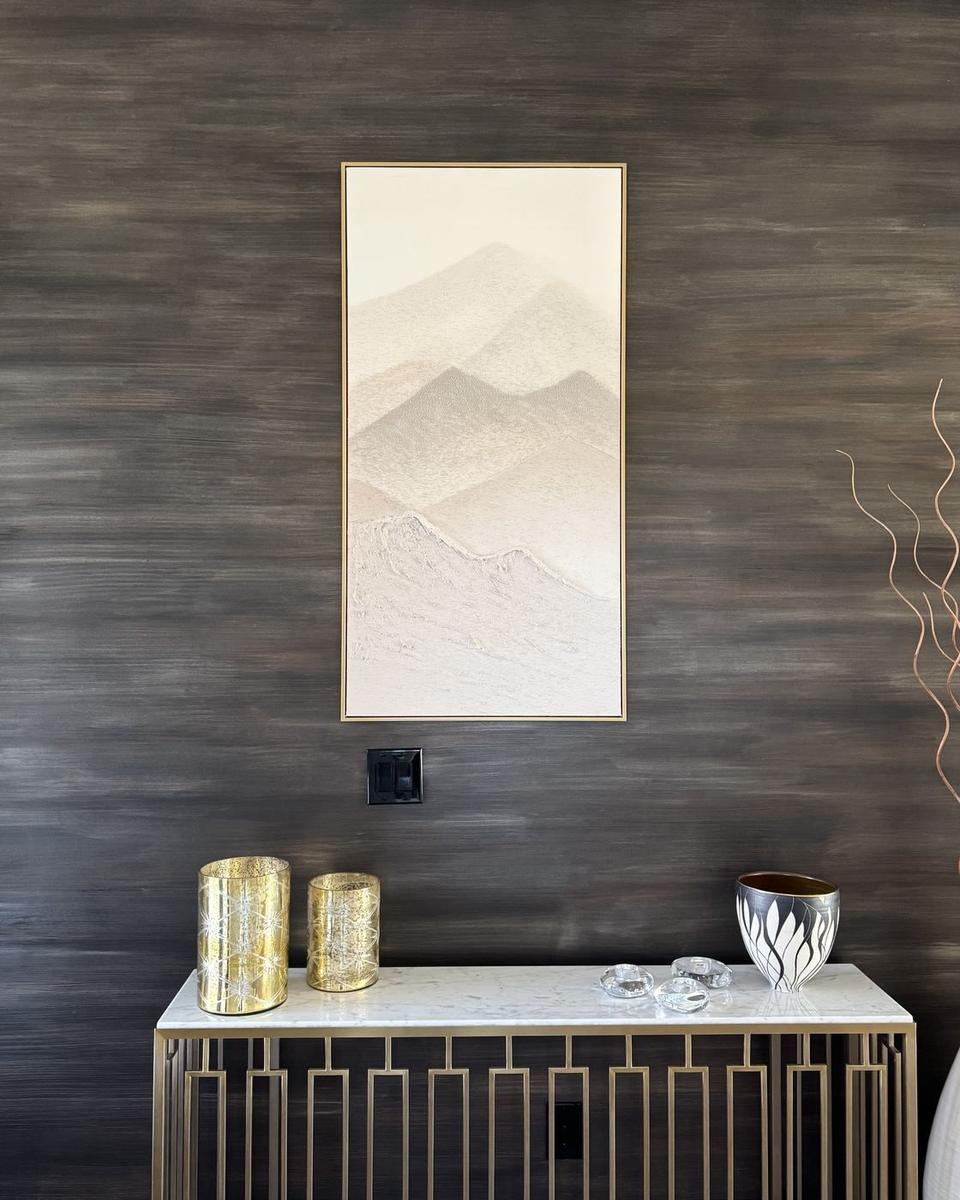 Textured accent wall with framed mountain art and console table